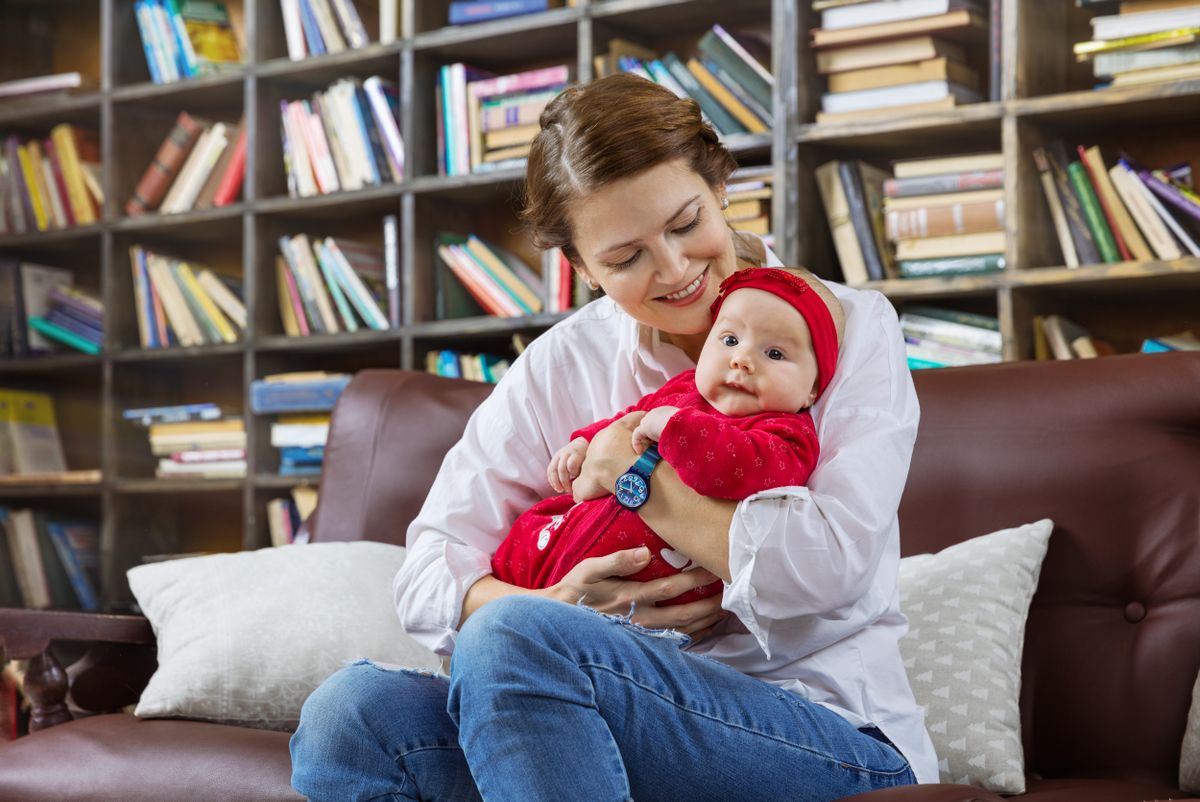 Young,Woman,And,Her,Baby,Daughter,On,Couch,In,Library