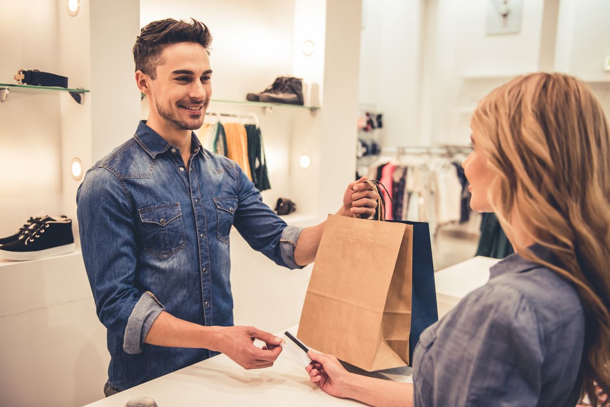 Handsome,Shop,Assistant,Is,Smiling,While,Giving,Purchases,And,Credit