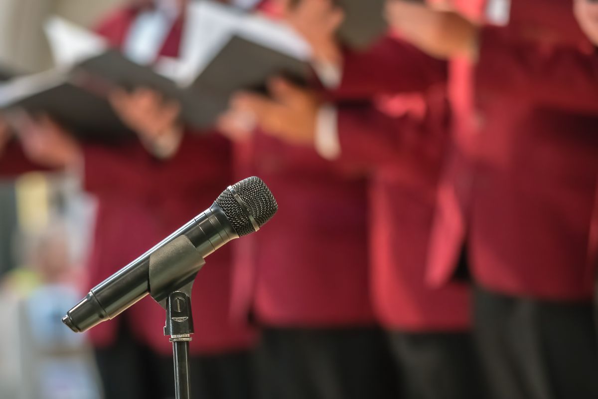 Microphone,On,A,Stand,In,Front,Of,Mens,Choir,Members