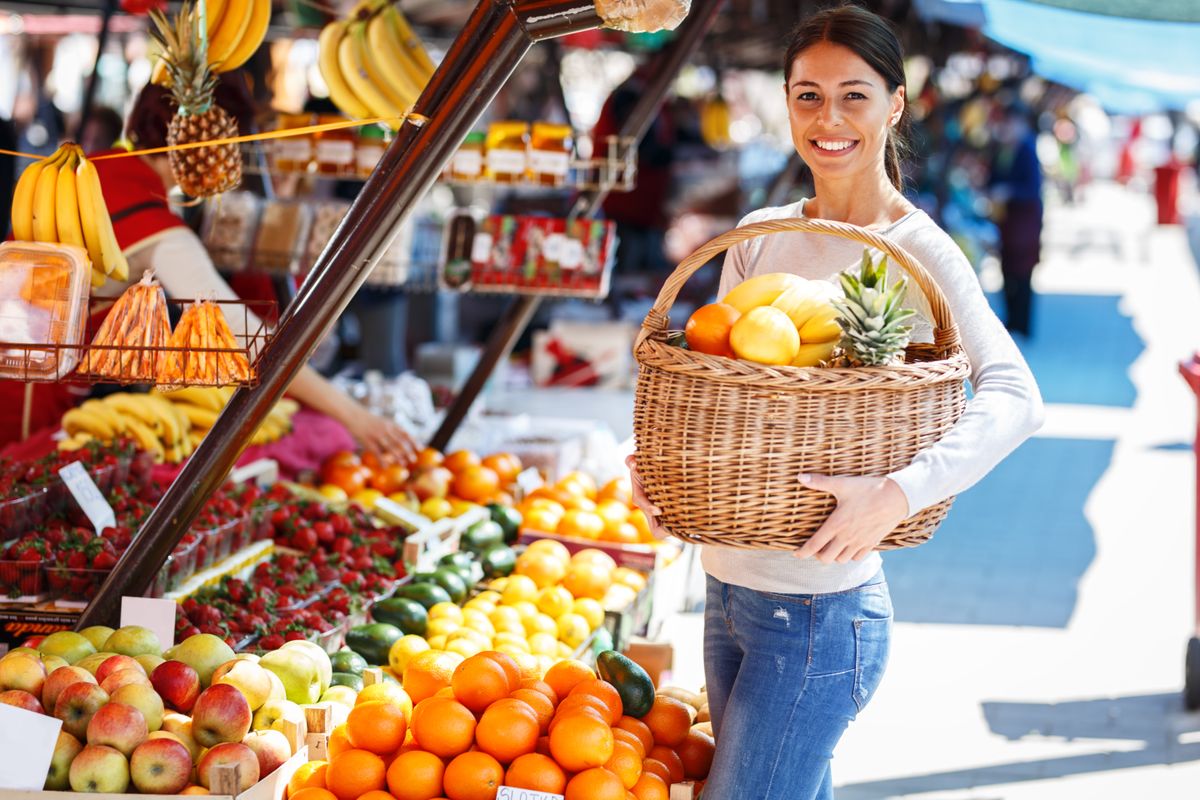 Young,Woman,On,Street,Market,Holding,Basket,Full,Of,Fruits