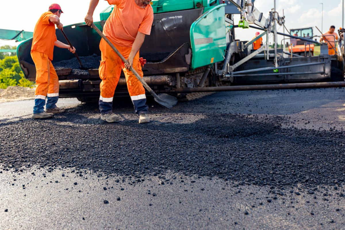 Few,Workers,Are,Using,Shovels,To,Level,Hot,Tarmac,On